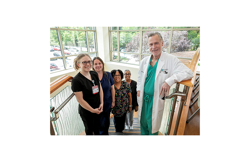 dr irvin smiling on a staircase surrounded by nurses